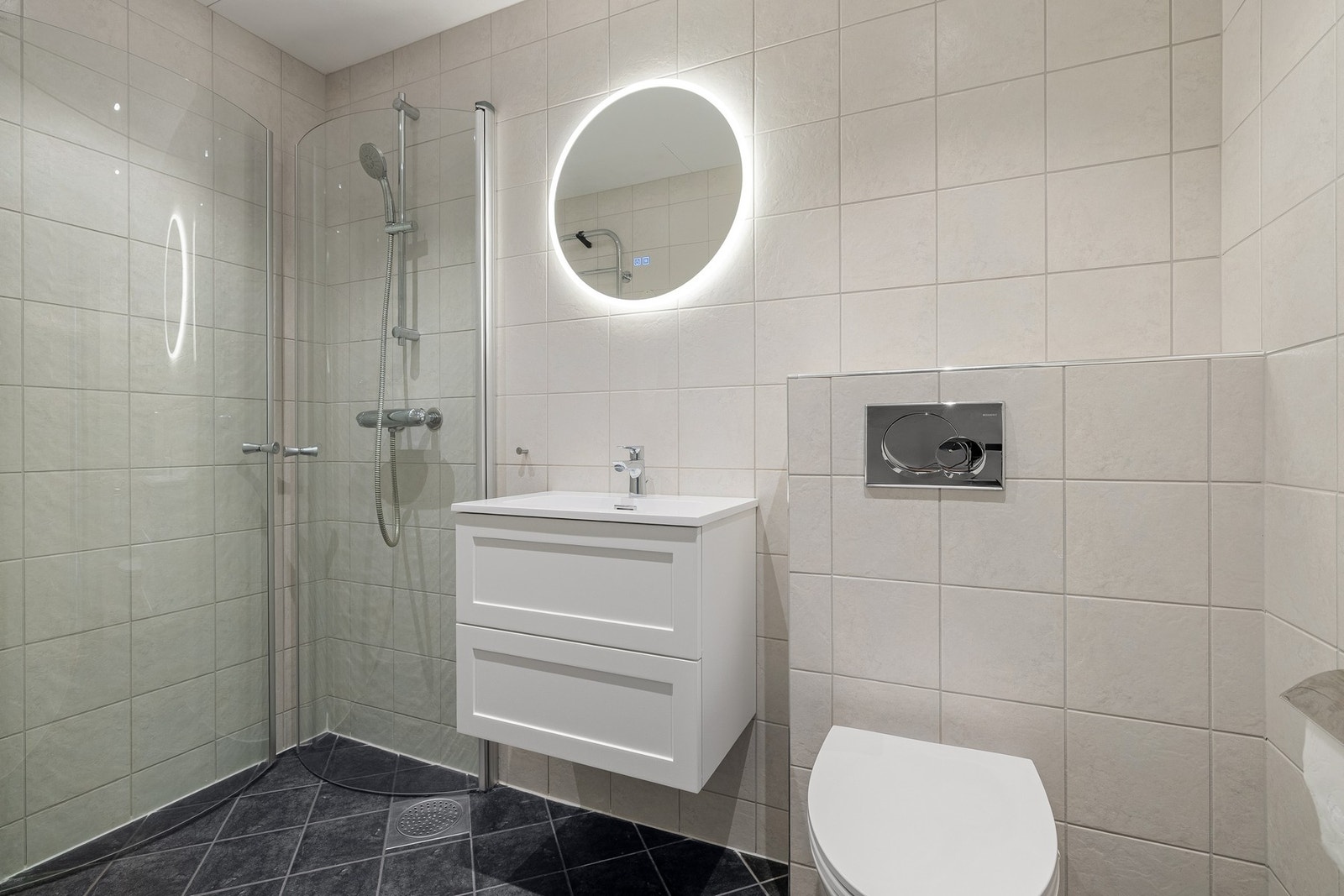 Badet fremstår som romslig og funksjonelt, med en lys og tidløs innredning og behagelige flislagte overflater. Galleribilde