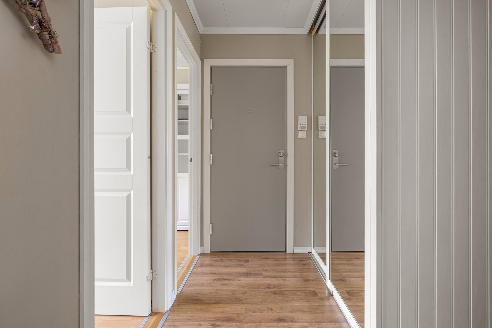 Du ønskes velkommen inn i en lys og romslig entré med god oppbevaringsplass i innebygde garderobeskap - ideelt for yttertøy og sko. Gulvet er belagt med laminat, og veggene har moderne smartpanel. Fra gangen har du praktisk tilgang til de fleste rom i lei Galleribilde
