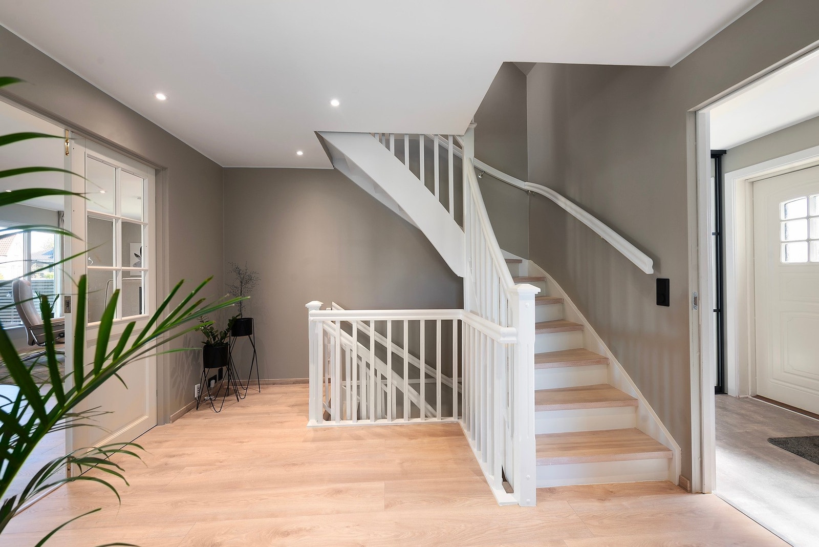 De nydelige fargetonene fortsetter videre inn i hallen og det er hvitmalt himling med spotter og lekker laminat på gulvet. I hele hovedetasjen er det vannbåren gulvvarme Galleribilde