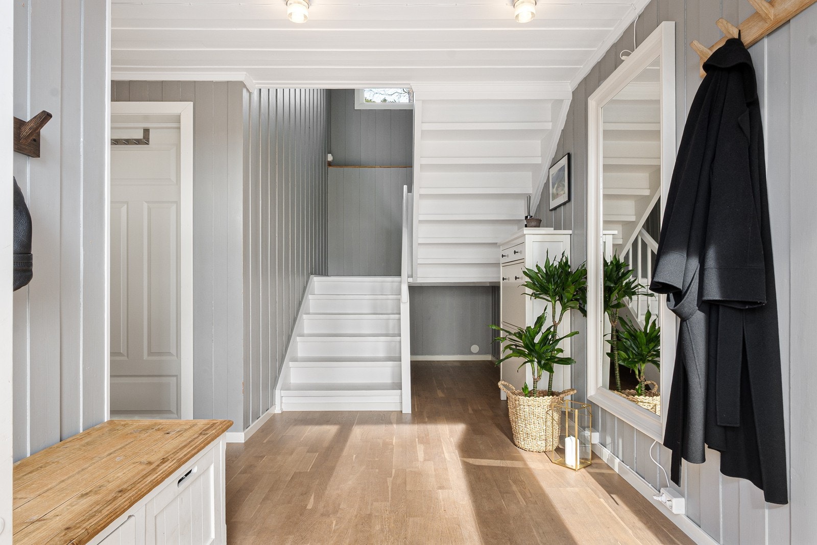 Hvitmalt trapp fører opp til boligens hovedetasje. Galleribilde