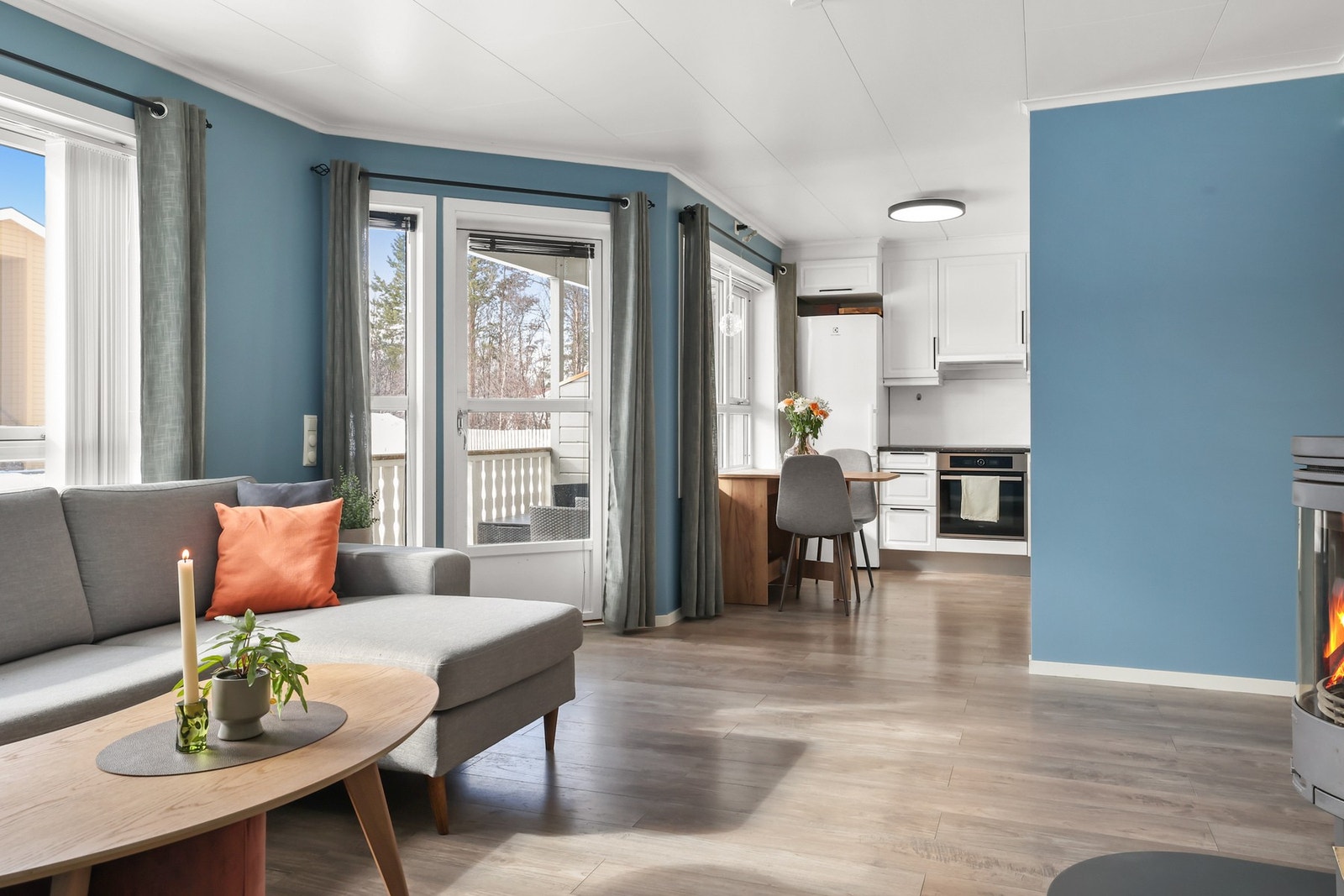 Gulvvarmen gir komfort året rundt, og den åpne løsningen mot kjøkkenet gjør rommet perfekt for både hverdagsliv og sosiale sammenkomster Galleribilde