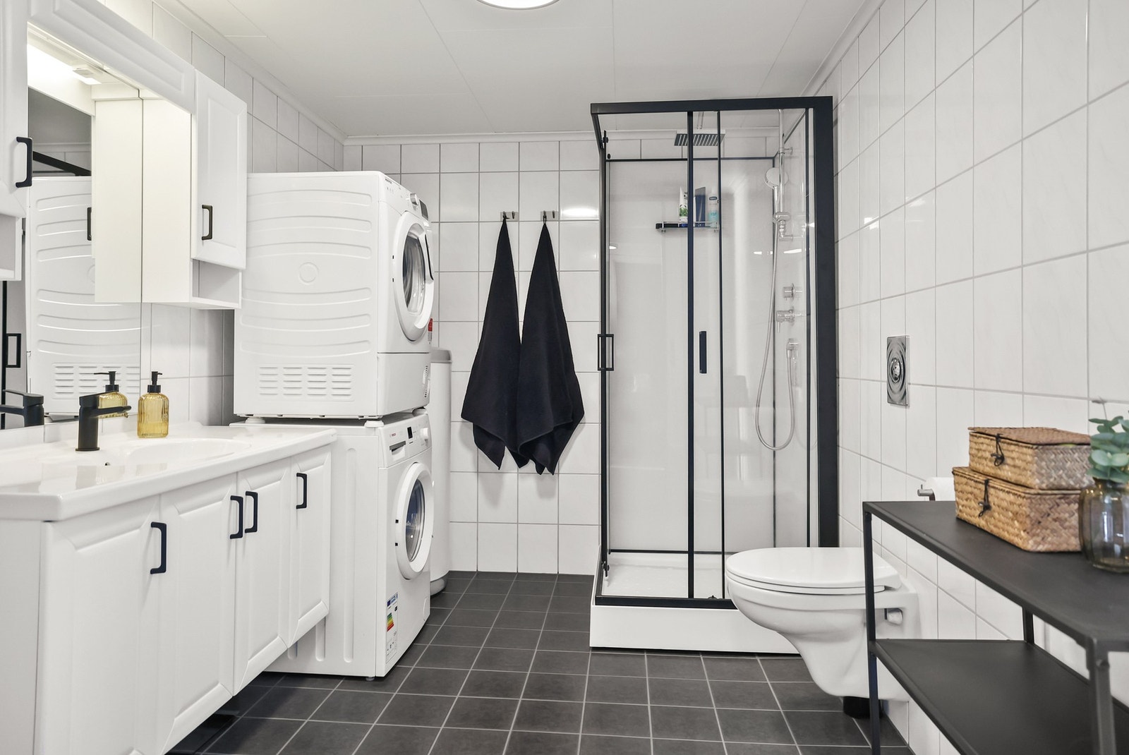 Badet er flislagt med gulvvarme og utstyrt med dusjkabinett, servant, speil med stikkontakt, vegghengt skap og mekanisk avtrekk. Galleribilde