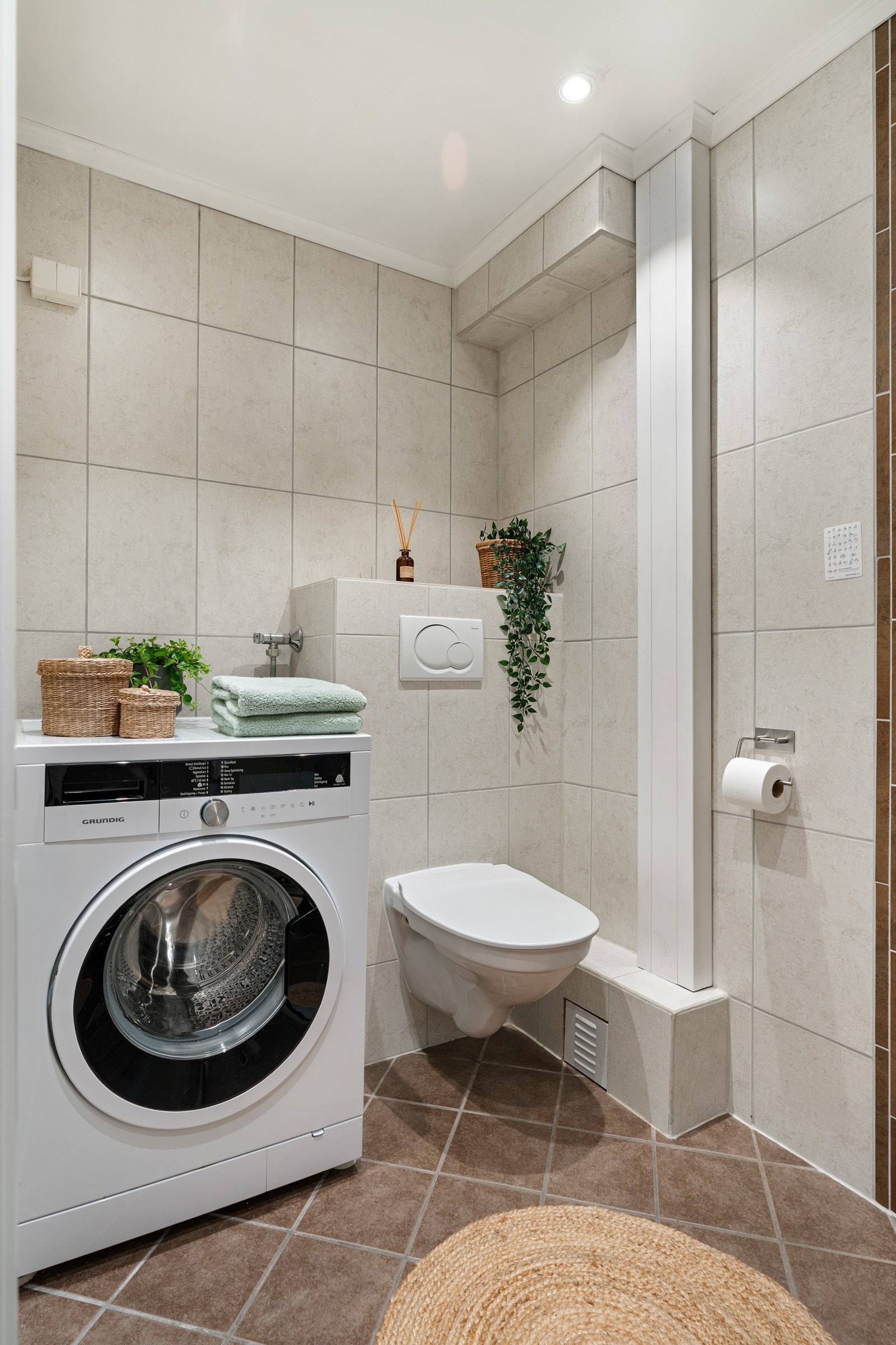 Badet er utstyrt med dusjhjørne med innfellbare dusjdører, gulvvarme, vegghengt servant, vegghengt toalett, speil og opplegg for oppvaskmaskin. Galleribilde