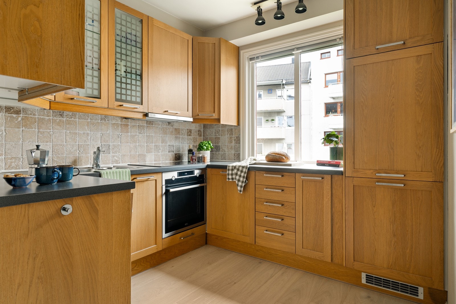 Tidløst kjøkken med innredning bestående av folierte skrog med profilerte fronter og laminert benkeplate med nedfelt oppvaskkum og platetopp. Galleribilde