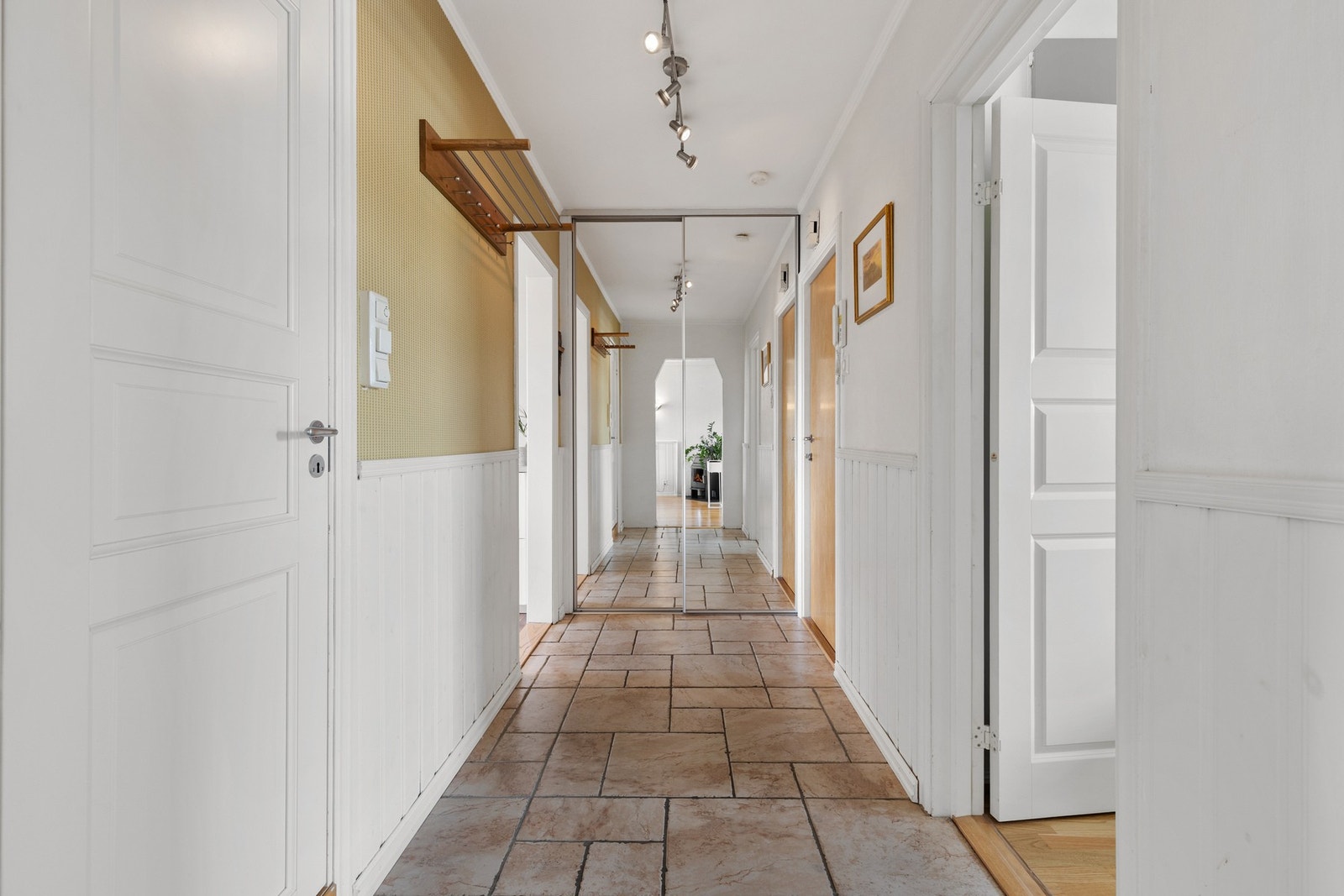Romslig entré med skyvedørsgarderobe og callinganlegg på vegg ved inngangsdør Galleribilde
