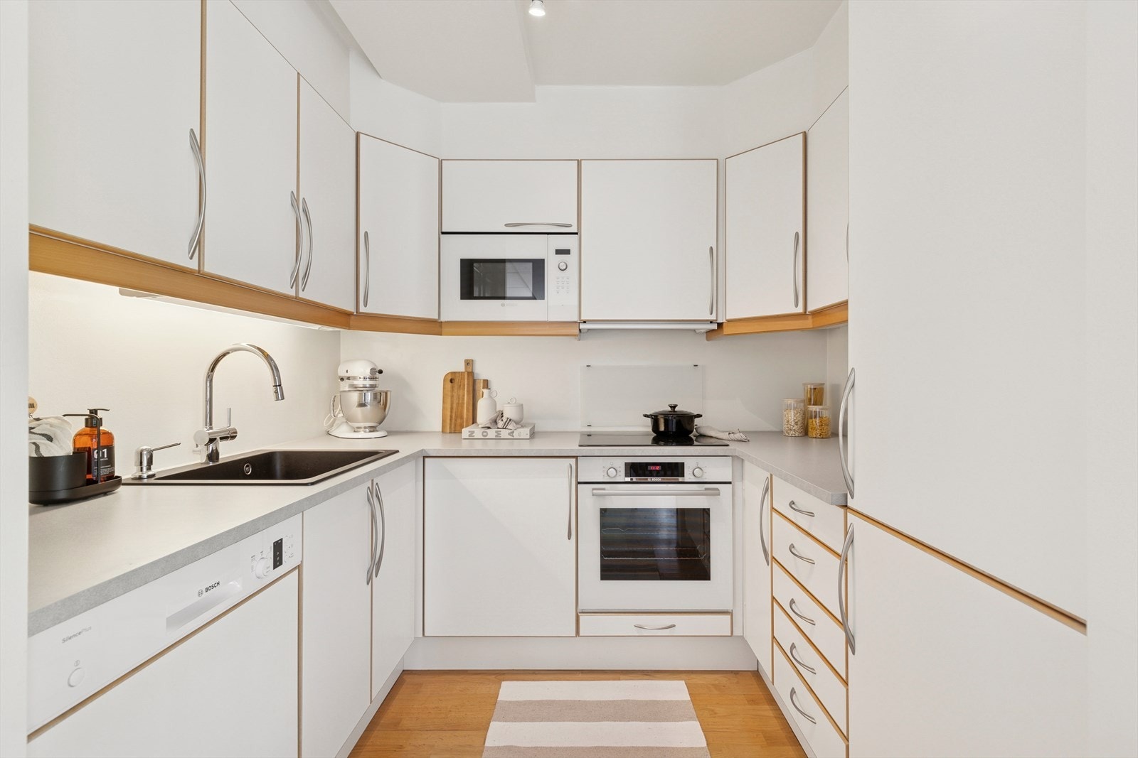 Romslig, lyst og svært praktisk kjøkken som har innredning med hvite, glatte fronter og benkeplate i laminat. Galleribilde