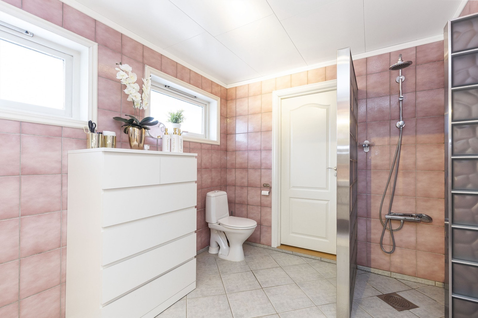 Badet har speilskap med overlys og vegghengte høyskap. Servantskap med heldekkende servant og skuffer. Dusj på gulv med hånd- og takdusj og vegger av glassbyggerstein. Galleribilde