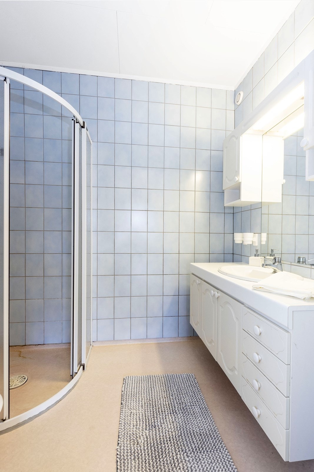 Flislagt vegger og gulv med gulvbelegg og malte himlingsplater i tak. Vegghengt servantskap med nedfelt servant og laminert benkeplate. Galleribilde