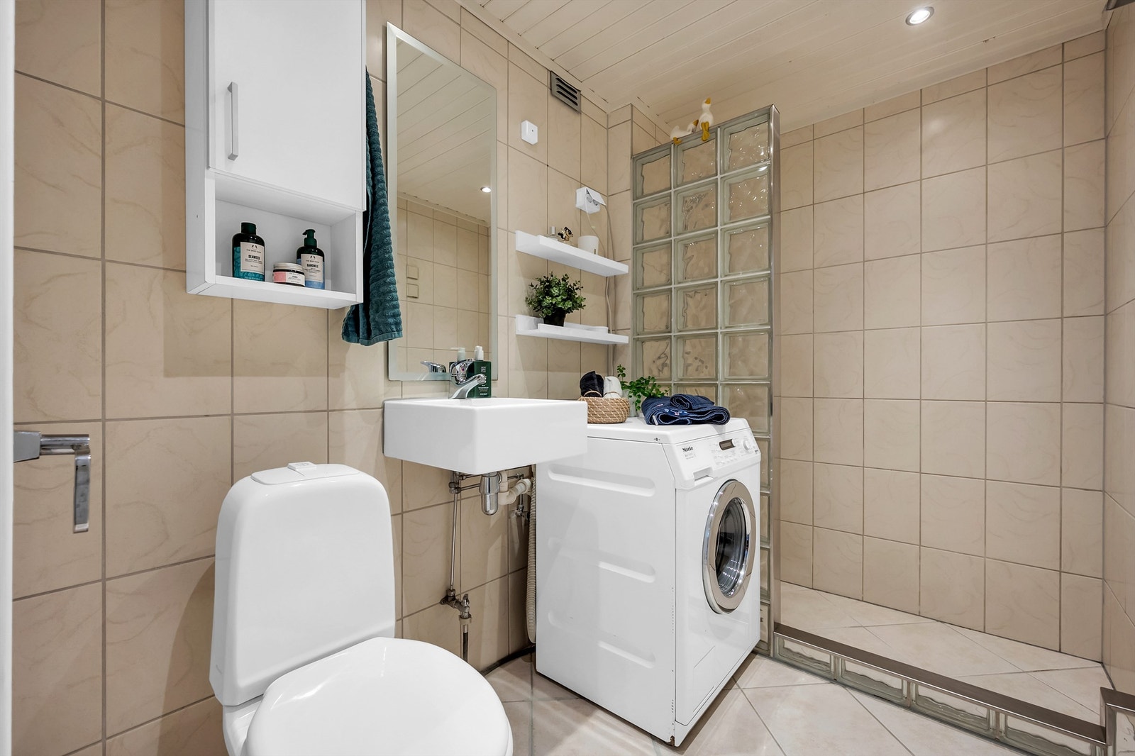 Flislagt bad med større dusjsone. Vaskemaskin fra Miele medfølger. Galleribilde