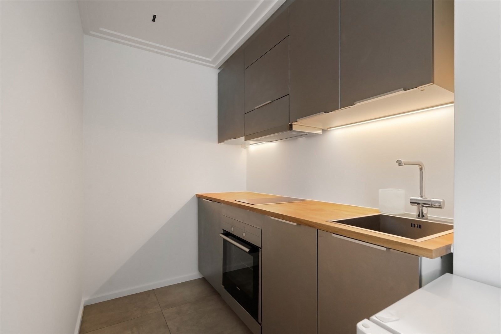 Kjøkken fra 2018 med glatte børstet stål / aluminiumsfronter, heltre eik benkeplate med nedfelt vaskekum og induksjon platetopp. Integrert i innredningen er stekeovn, kjøleskap og oppvaskmaskin. Galleribilde