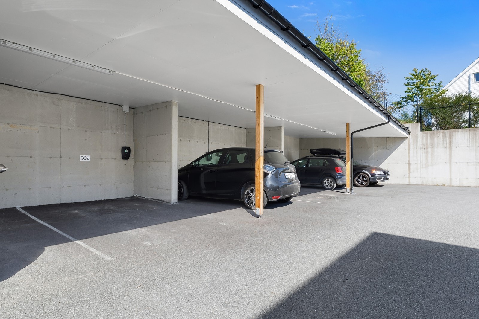 Parkering i carport med hurtiglader for bil, samt gjesteparkering på fellesareal. Galleribilde