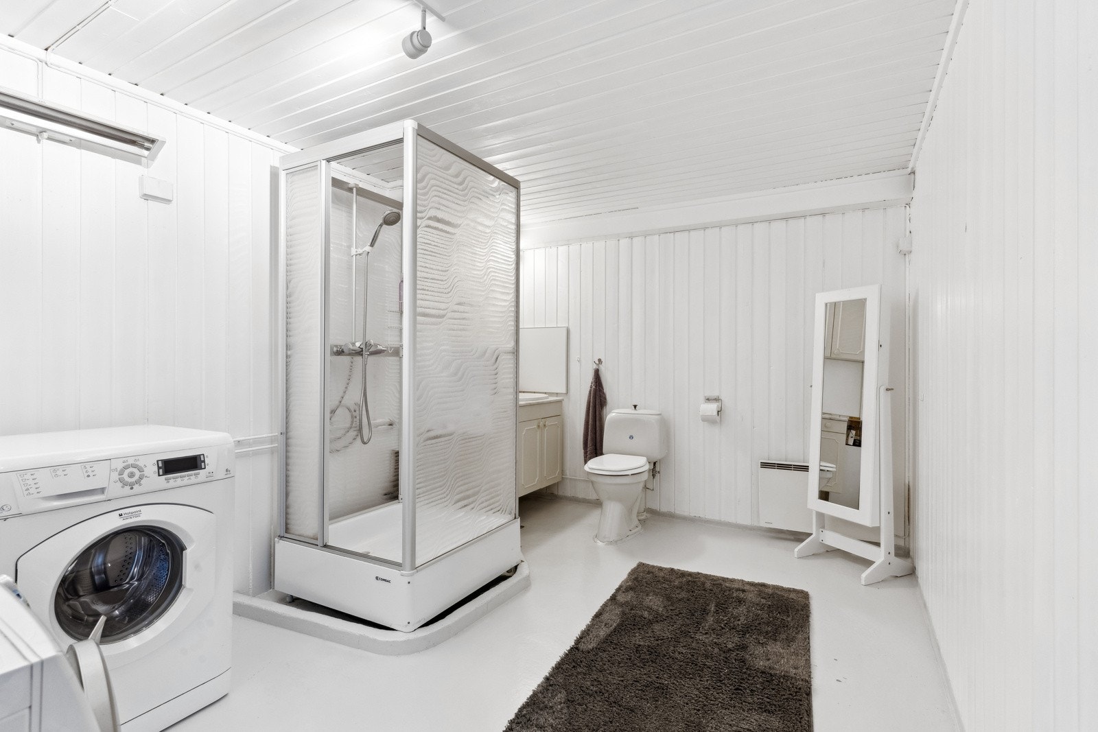 Bad/vaskerom i underetasjen med lukket dusjkabinett, toalett, servant og opplegg for vaskemaskin. Galleribilde
