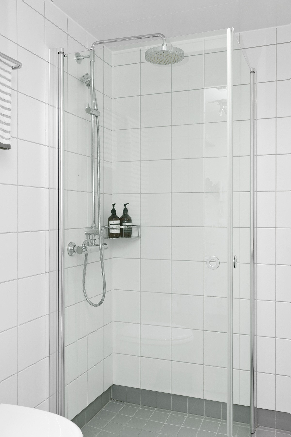 Rommet er innredet med vegghengt servantinnredning med skuffer, vegghengt speil, vegghengt skap over servant, vegghengt toalett og dusjhjørne med glassdører og vegghengt dusjarmatur med regndusj Galleribilde