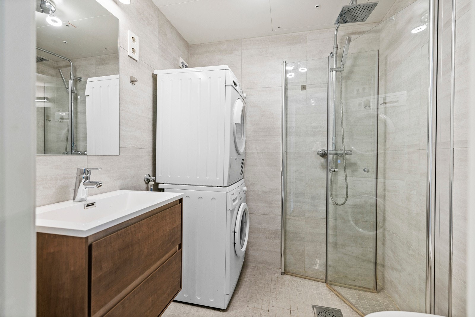 Pent flislagt bad med varmekabel i støp som styres over en trinnløs digital regulator. Videre er det vegghengt speil med overliggende lyslist/armatur. Galleribilde