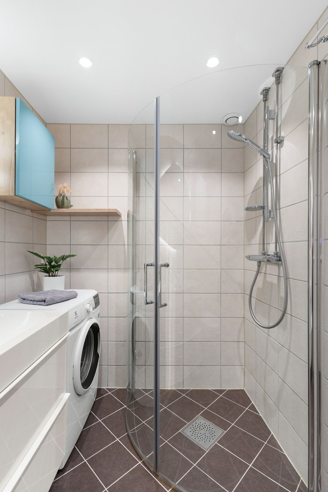 Badet er innredet med benkeskap med servant, innfellbare dusjdører i glass, vegghengt toalett, og opplegg for vaskemaskin. Galleribilde
