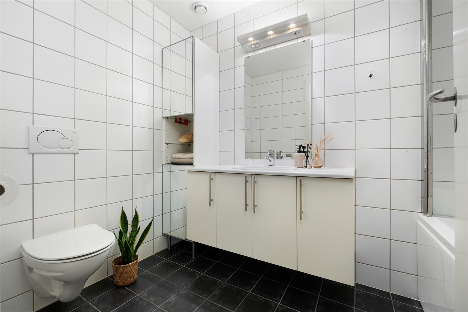 Stilfullt baderom på 5 m² som er flislagt fra topp til tå, utstyrt med mekanisk avtrekk, servantskap, veggmontert WC og elektriske varmekabler i gulv. Galleribilde