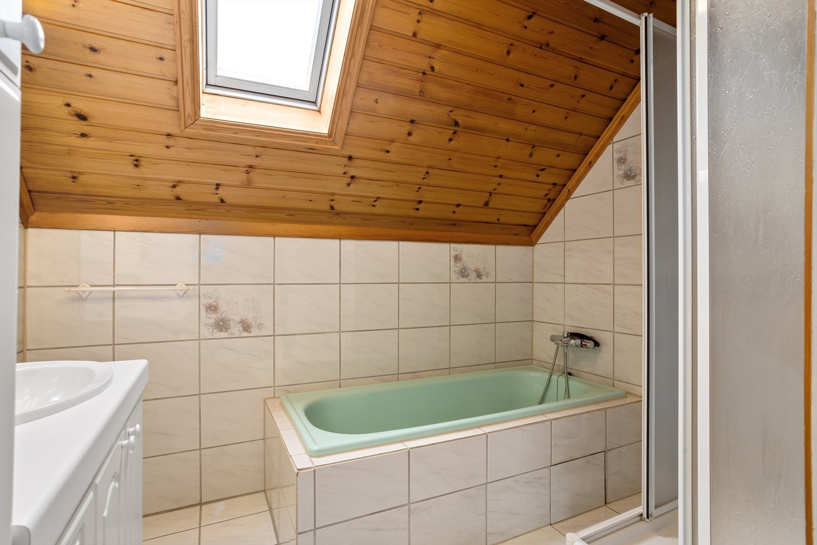 Badet er innredet med både dusjhjørne og innfliset badekar. Plassert i 2. etasje med naturlig lys fra takvindu. Galleribilde