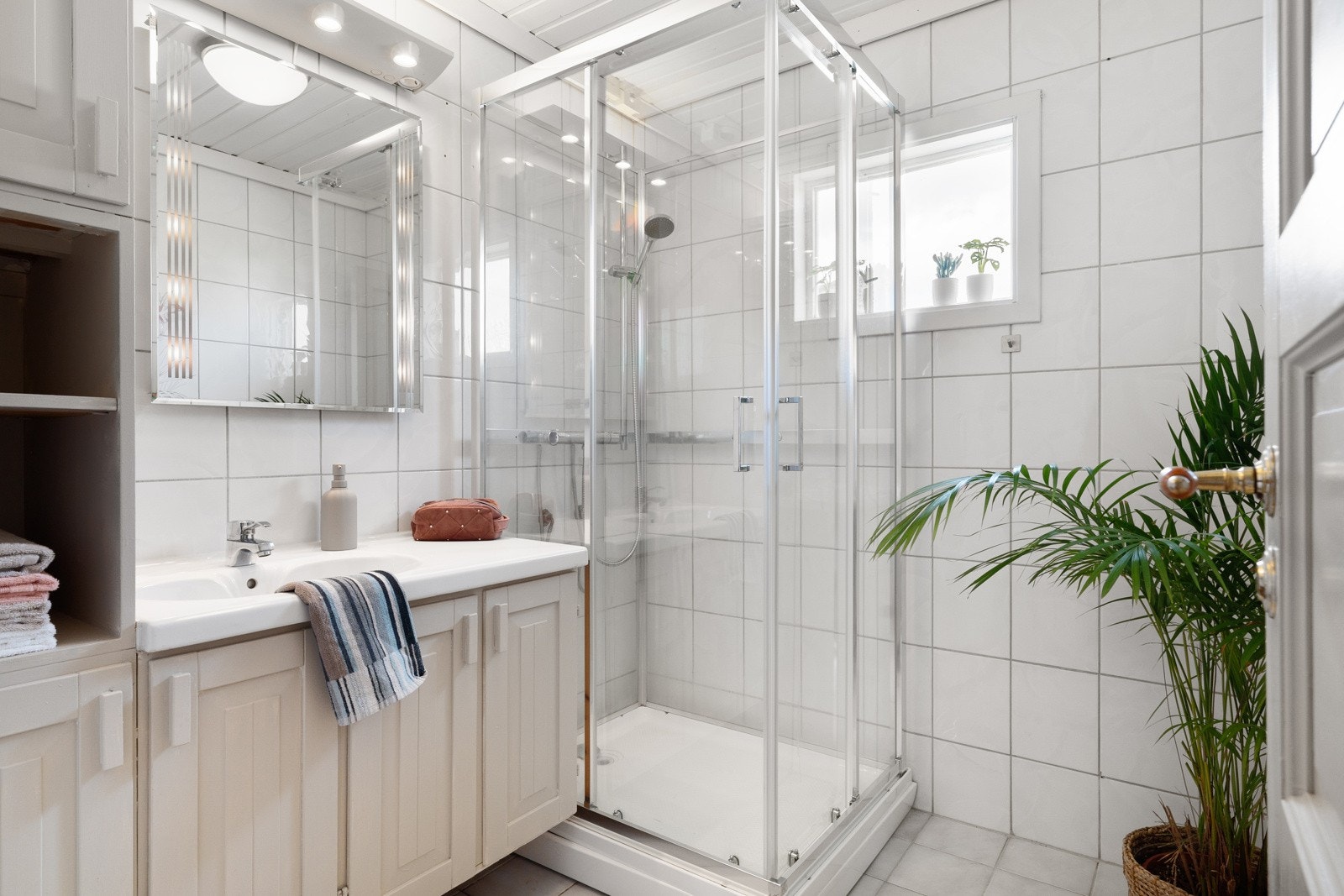 Det 3,7 kvm store badet er flislagt med behagelig gulvvarme. Det er god plass til oppbevaring av baderomsartikler i et romslig baderomsmøbel. Det ble satt inn nytt dusjkabinett i 2024. Galleribilde