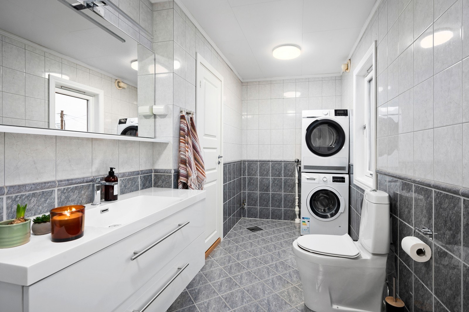 Rommet er innredet med moderne servantinnredning med speil over, dusjhjørne og wc. Spyleknapp på toalett er ødelagt. Mekanisk avtrekk med elektrisk styrt vifte. I tillegg er det plass og opplegg for vaskemaskin og tørketrommel Galleribilde