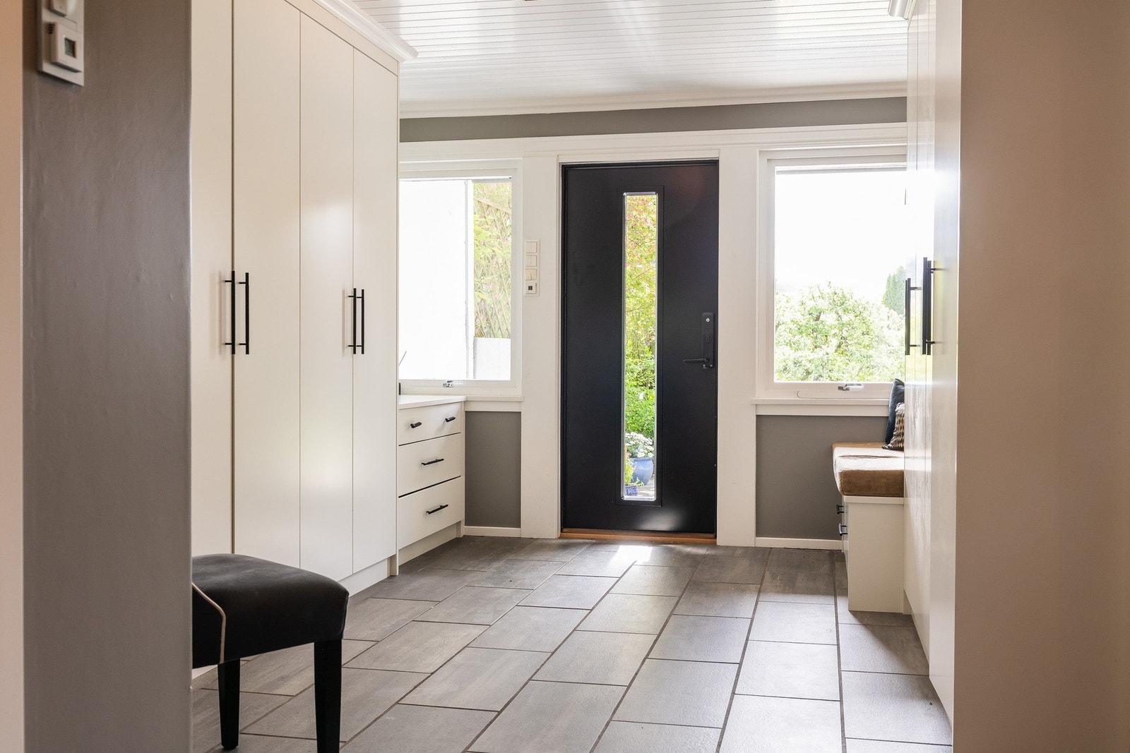 Romslig inngangsparti med plassbygget innredning og skifer fliser med gulvvarme. Galleribilde