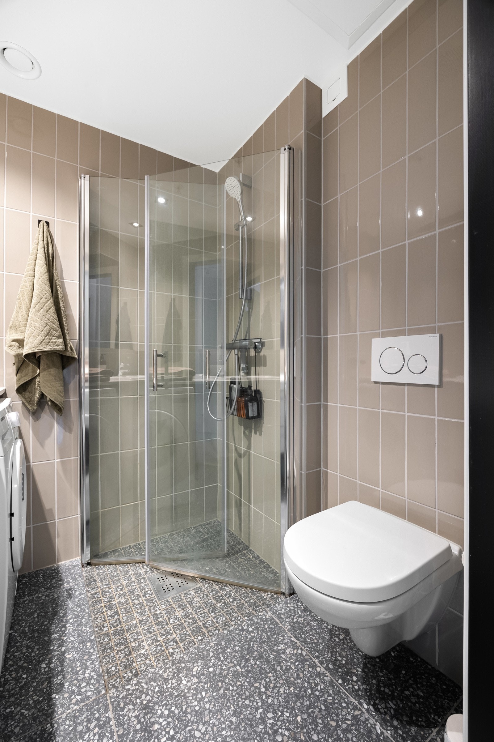 Badet inneholder servantinnredning med speilskap, dusjhjørne, vegghengt toalett og opplegg for vaskemaskin. Det er avtrekksventil i himlingen Galleribilde