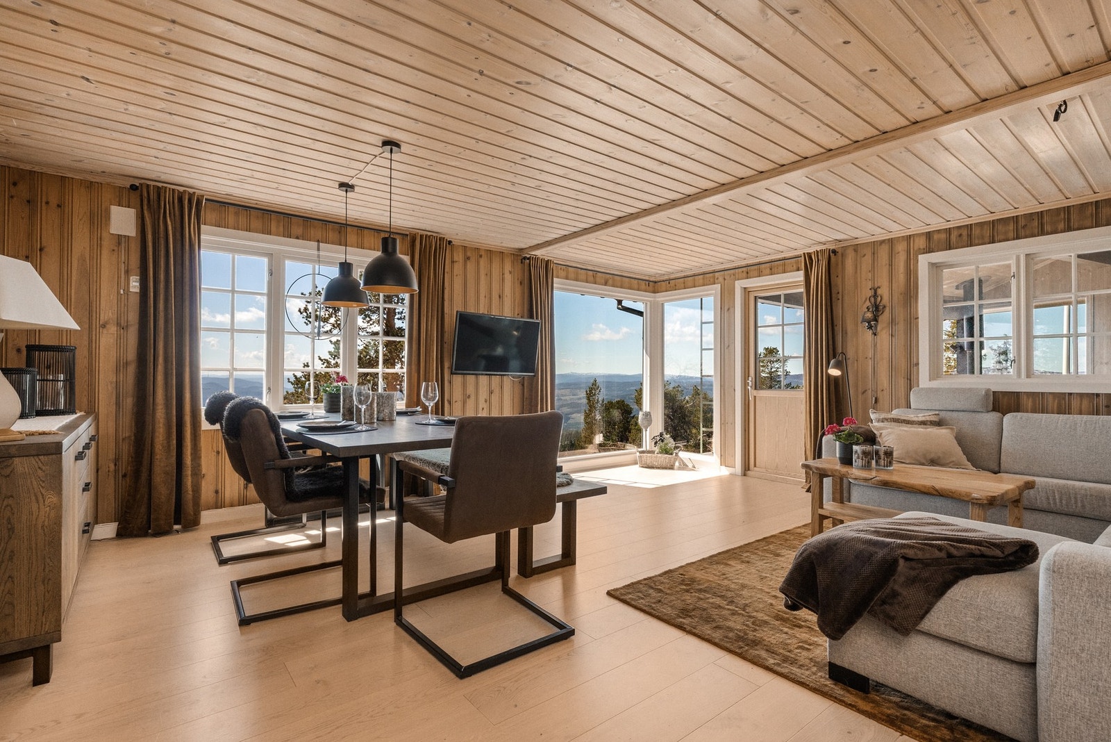 Fra vinduene flommer dagslyset inn og en kan kjenne på god romfølelse Galleribilde