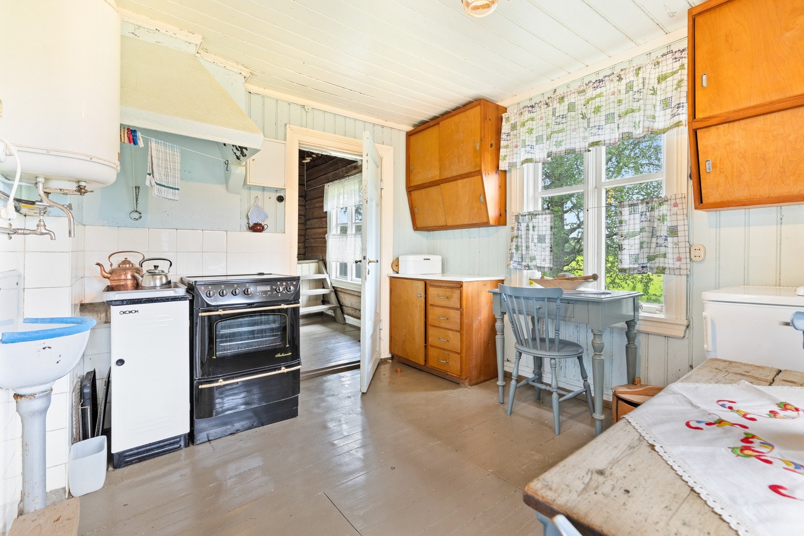 Innredning bestående av benkeskap og overskap, samt separat utslagsvask. Av hvitevarer medfølger komfyr og kjøleskap. Galleribilde