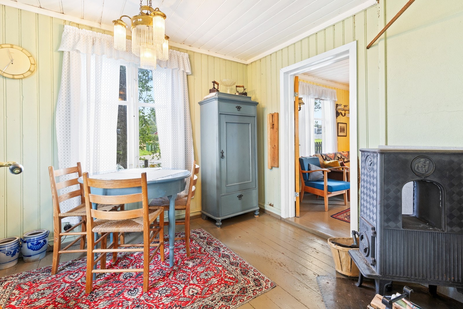 Rommet har malt panel på veggflater og i himling, samt originale heltre gulvbord. Den eldre peisovnen varmer godt på kalde sommerdager. Galleribilde
