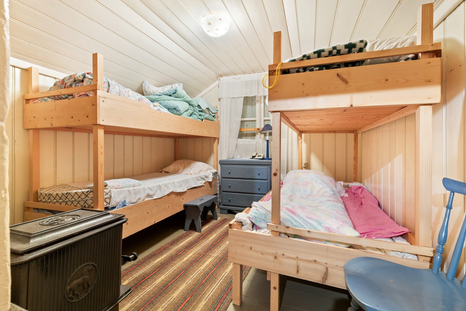 I boligens 2.etasje finnes et soverom med malt panel på veggflater, heltre gulvbord og peisovn. Det er et vindu i gavlvegg - p.t. forblendet. Galleribilde