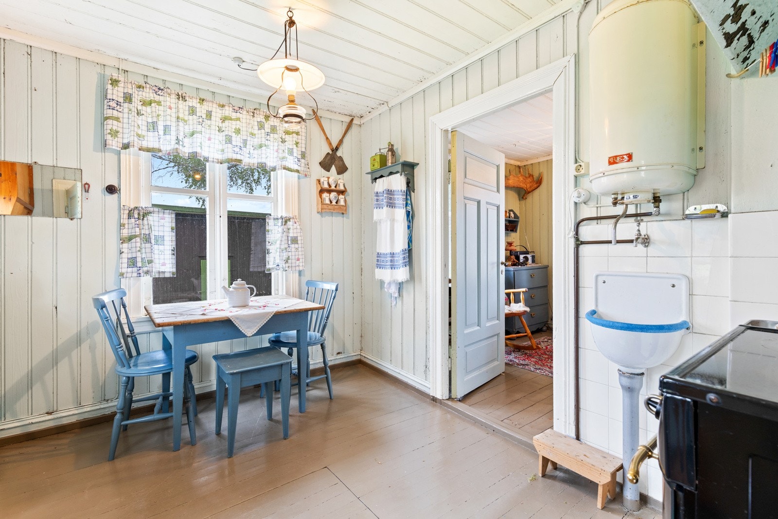 Stort eldre kjøkken med spiseplass. De store vindusflatene slipper inn rikelig med lys. Galleribilde