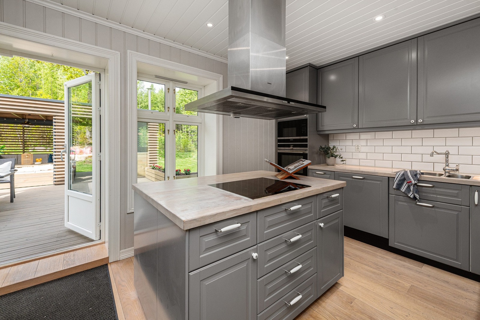 Kjøkkenøya med integrert koketopp og ventilator i stål, og skaper et elegant midtpunkt som inviterer til både matlaging og sosialt samvær. Galleribilde