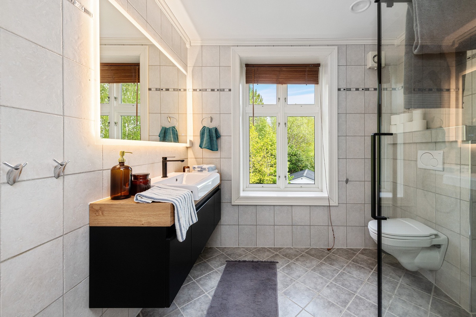 Badet i andre etasje har flislagt gulv med varme og grå fliser på vegger i tidløse nyanser. Galleribilde