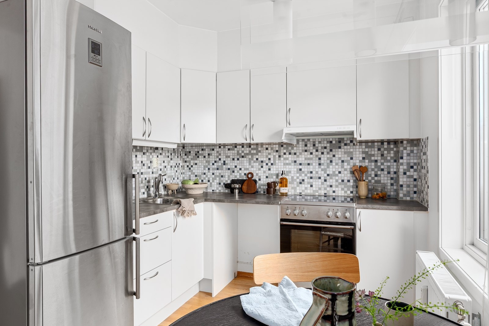 Lys og pen kjøkkeninnredning med glatte fronter og laminat benkeplate Galleribilde