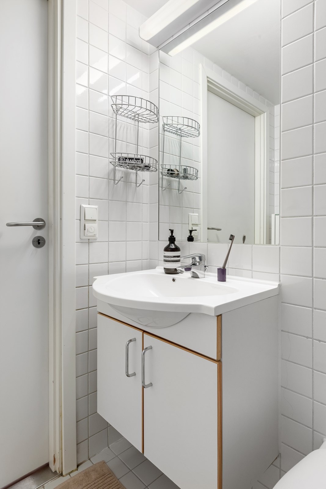 Baderommet er utstyrt med servant med innredning, dusj på gulv og veggfestet klosett Galleribilde