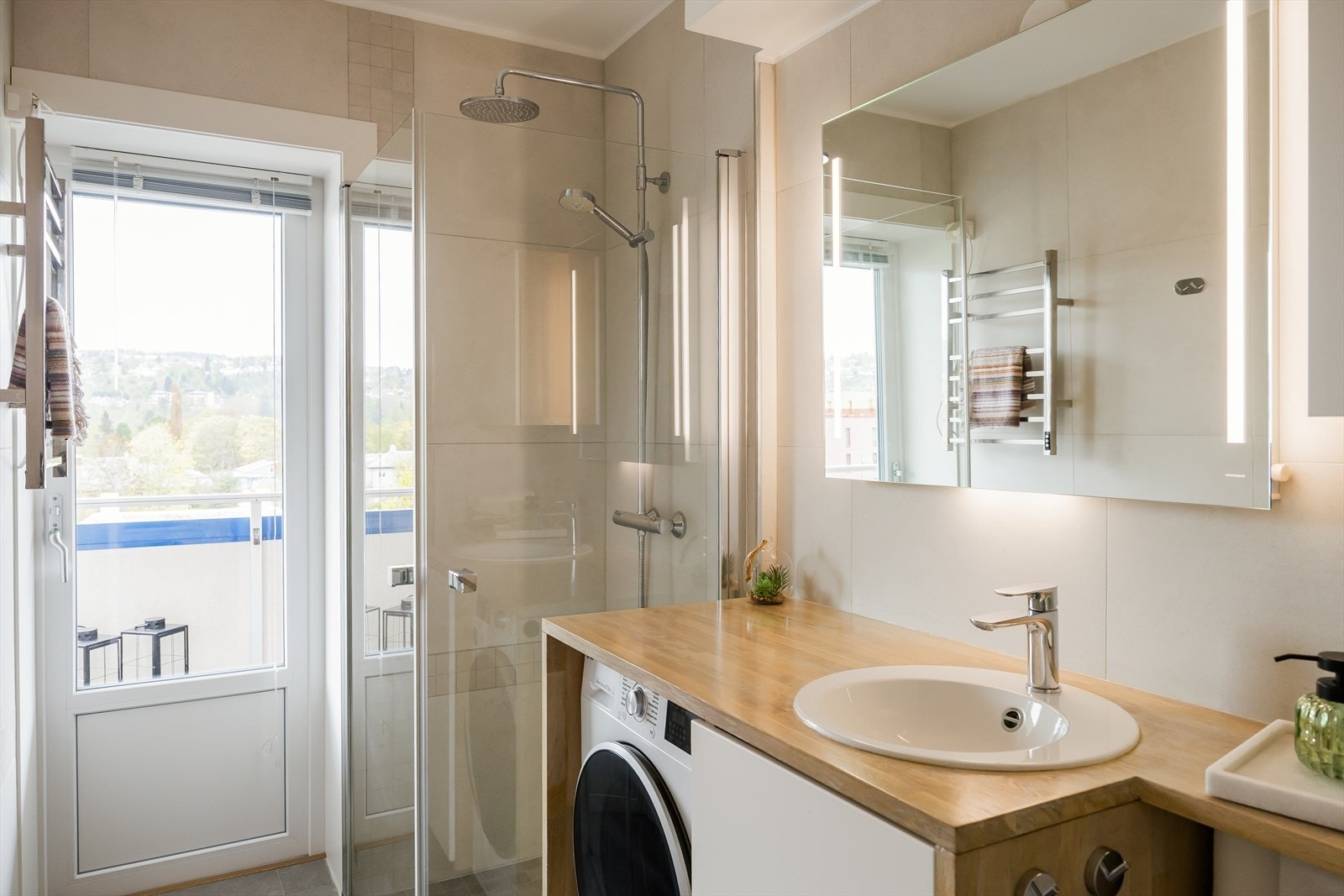 Badet har direkte utgang til balkongen og er utstyrt med blant annet opplegg for vaskemaskin, gulvvarme, speil med belysning og regnfallsdusj. Galleribilde