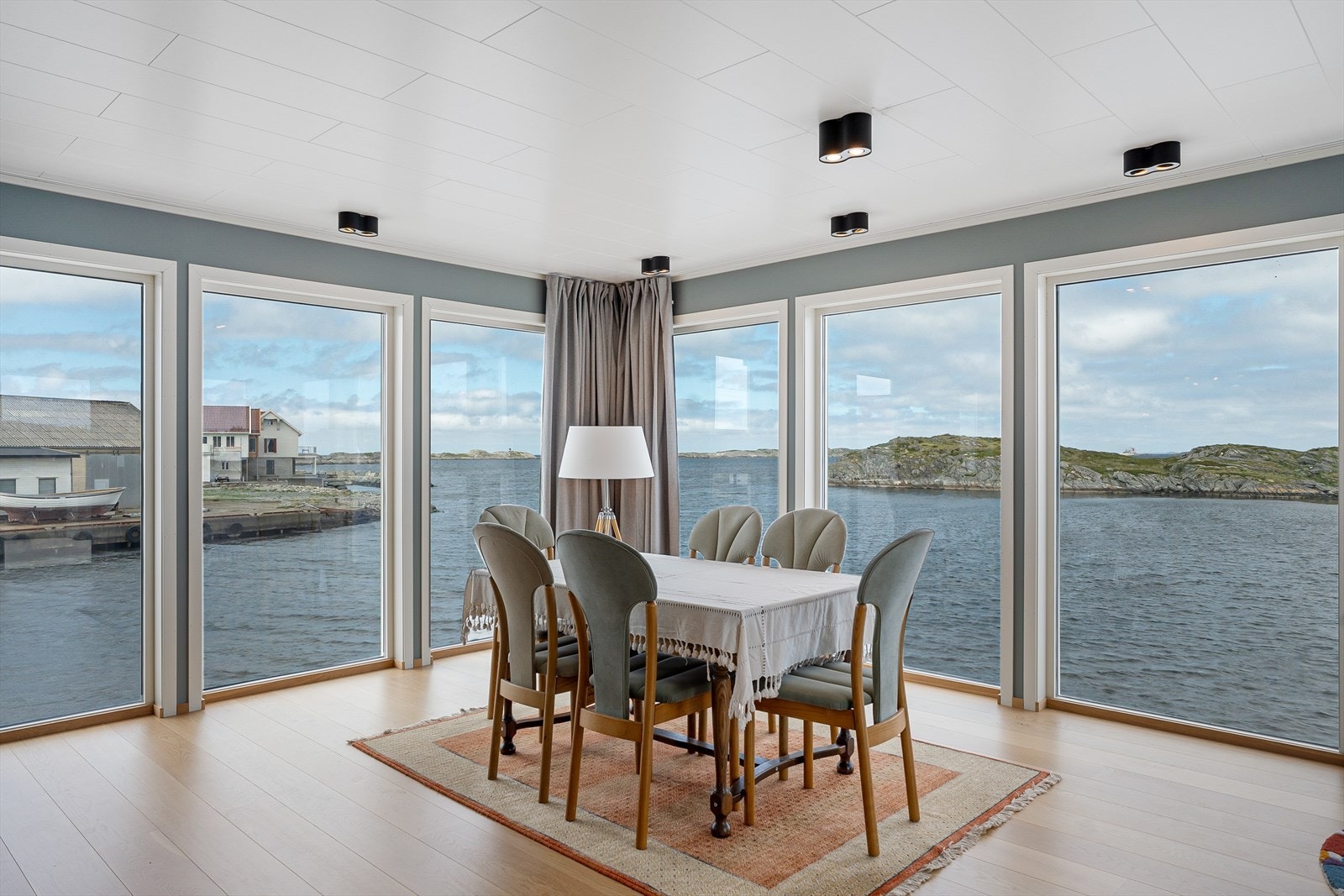 Fritidsboligen har store vinduer i deler av stuen som går fra gulv til tak, og som gir mye naturlig lys og en fantastisk sjøutsikt Galleribilde