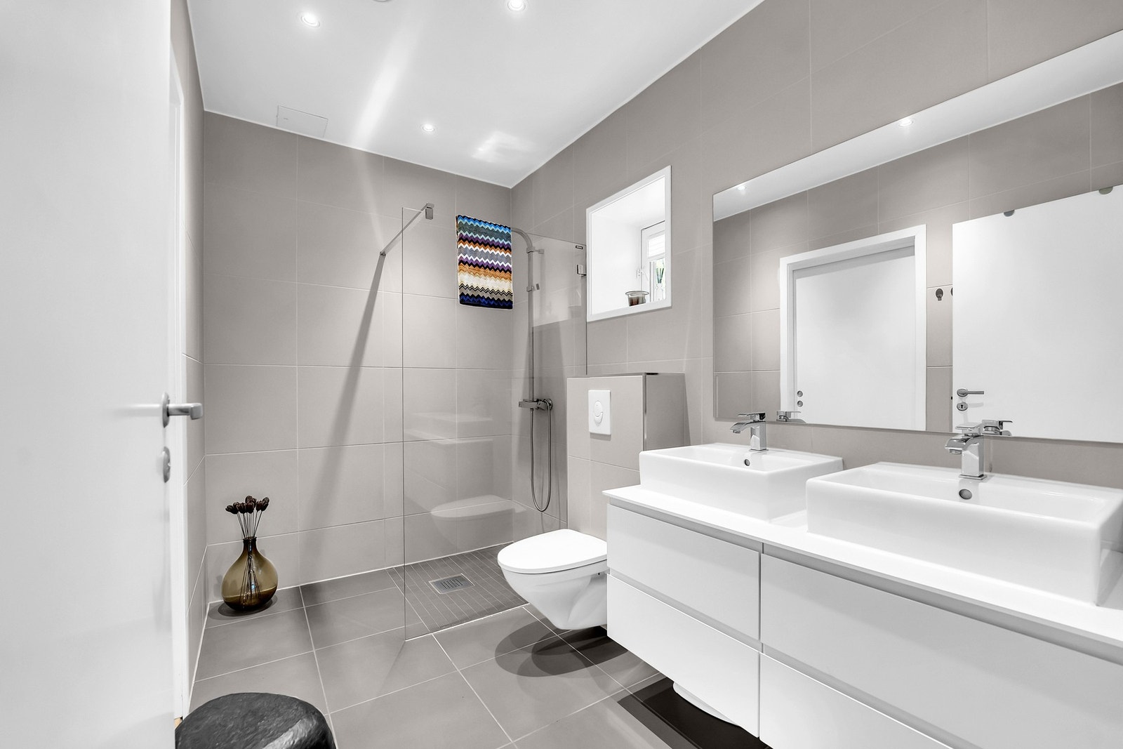 Badet er flislagt med moderne innredning, gulvvarme og regnfallsdusj - stilfullt og funksjonelt. Galleribilde