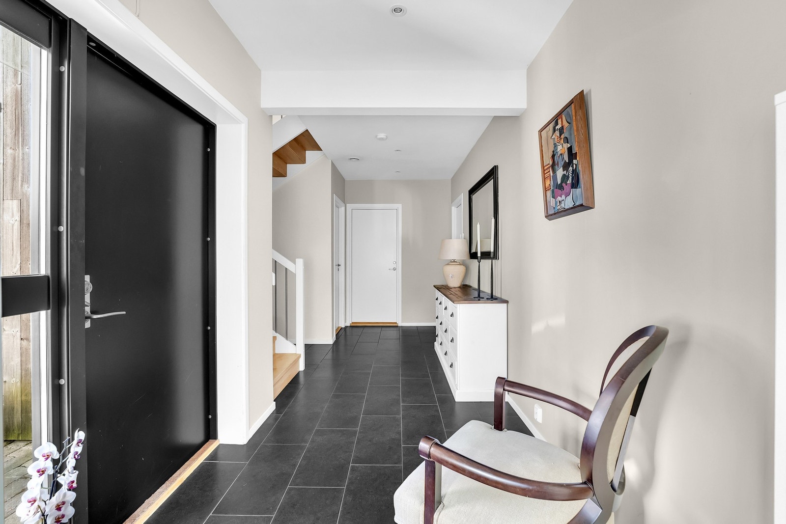 Velkommen inn i en romslig entré med slitesterke fliser og plass til både sko og yttertøy.
Ytterdøren har dessuten kodelås, noe som sørger for en enklere, nøkkelfri hverdag. Galleribilde