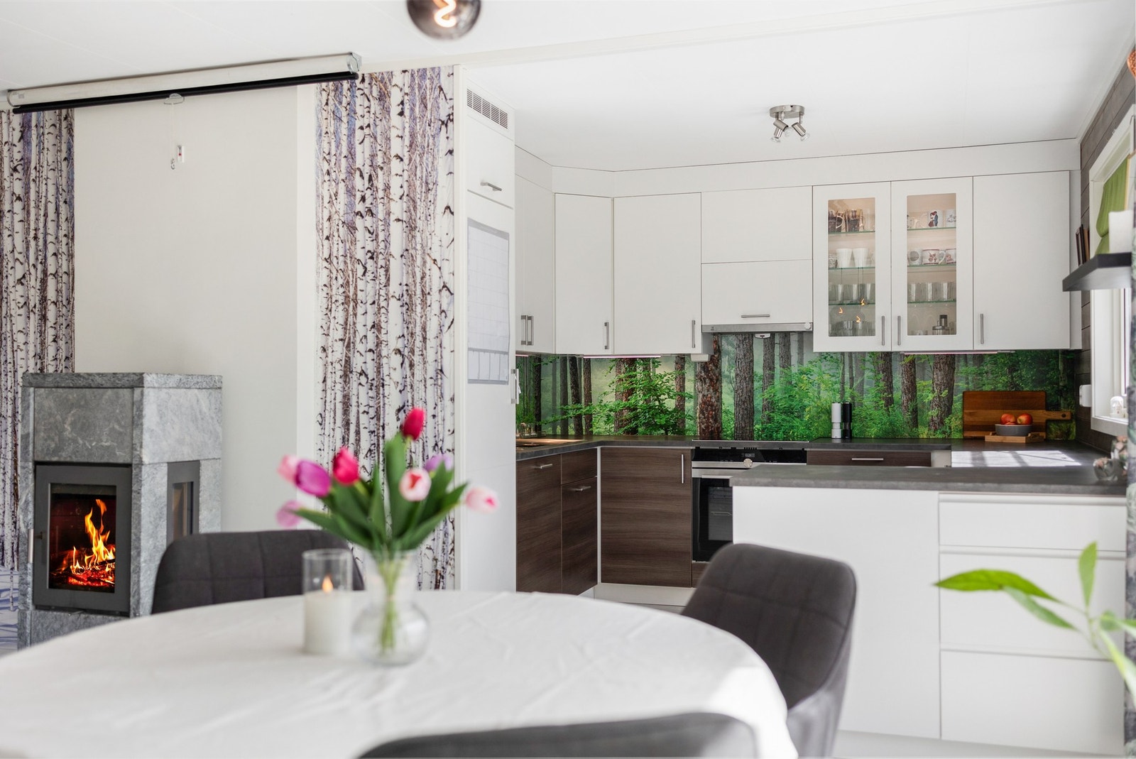 Den åpne løsningen mellom spiseplassen og kjøkkenet bidrar til flere sosiale soner selv ved matlagingen Galleribilde