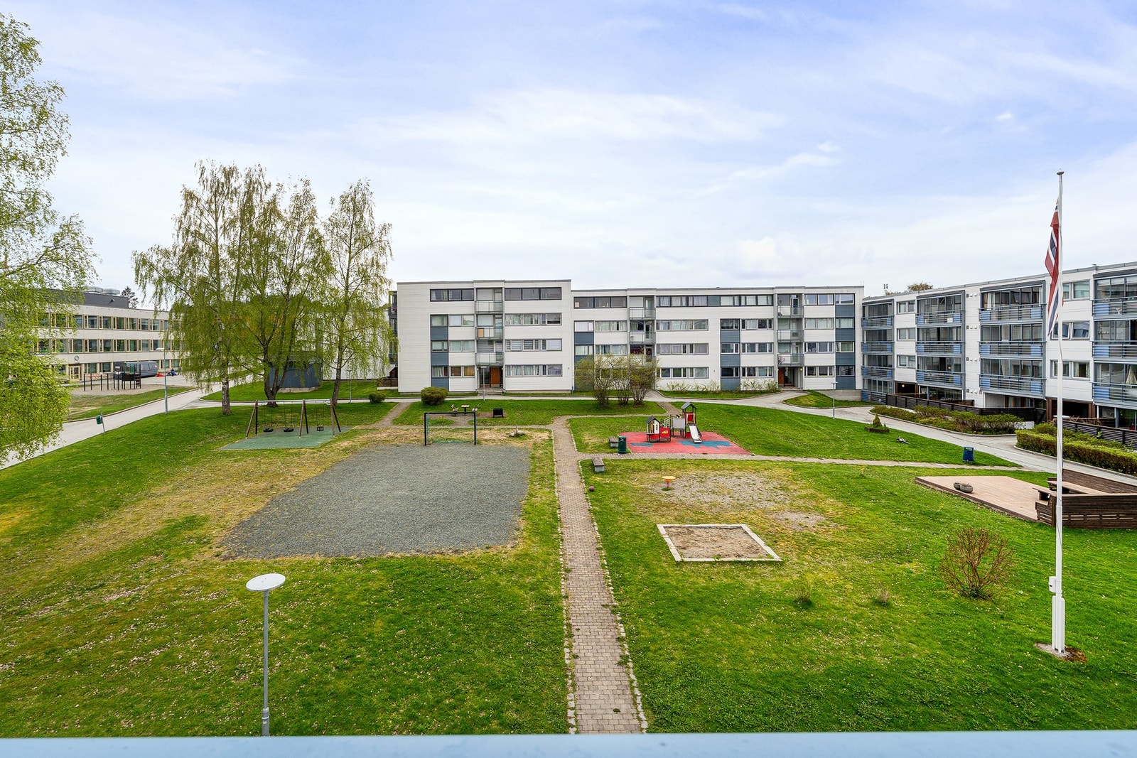 Vinduene på balkongen kan åpnes helt opp. Fredelig utiskt over tunet fra balkongen. Galleribilde