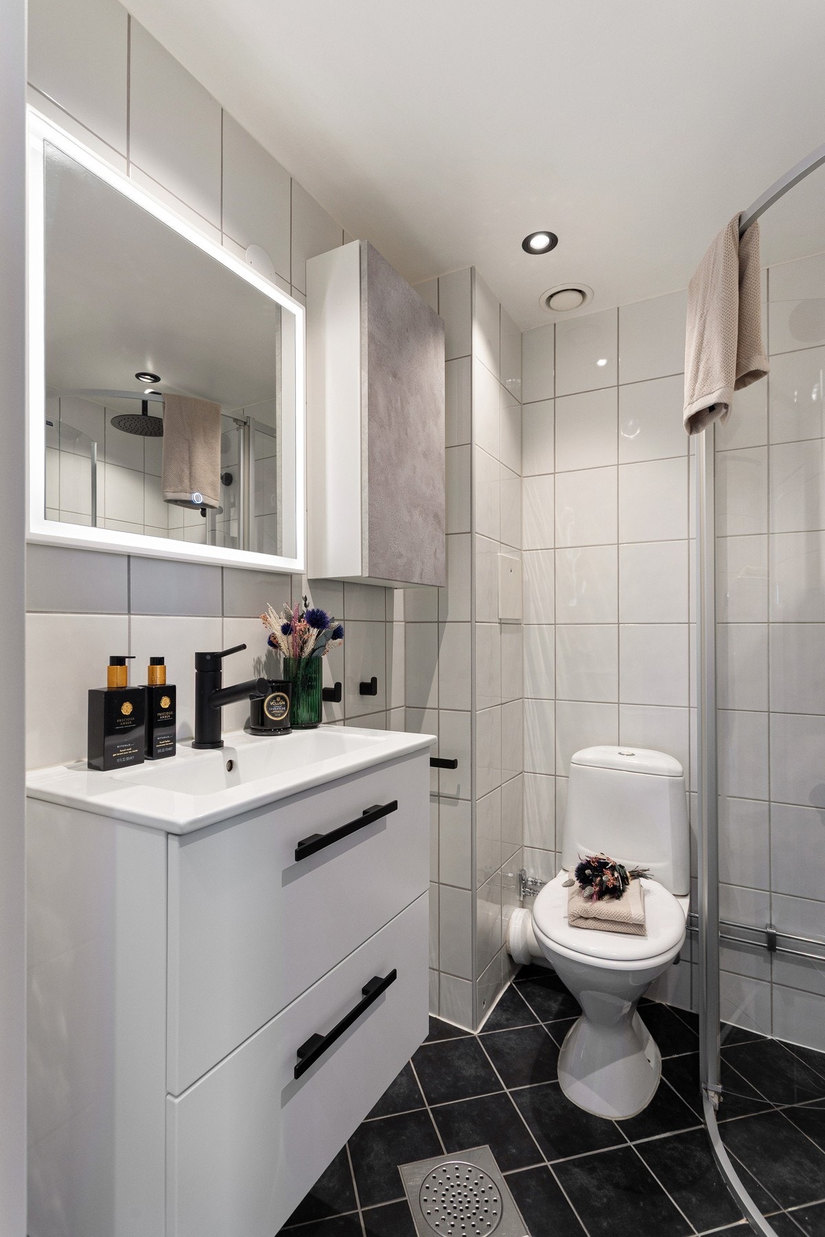 Innredningen består av nyere servantinnredning med to skuffer og speil med belysning rundt. VIdere er badet utstyrt med dusj og toalett. Galleribilde