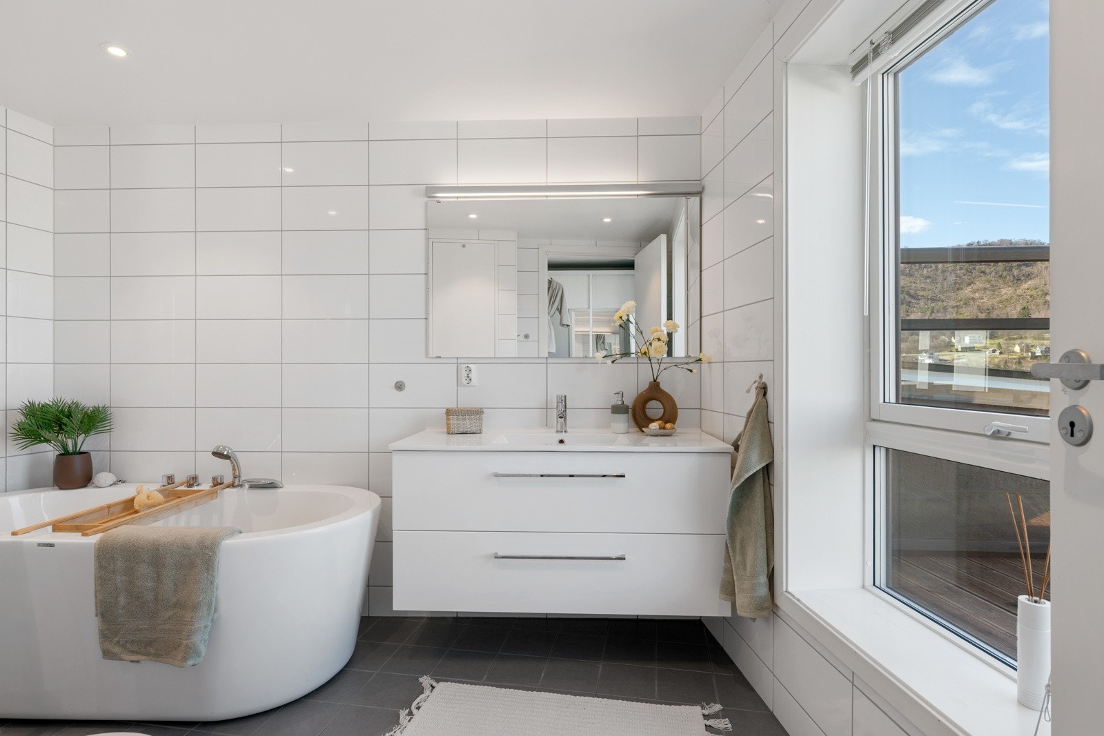 Badet har gulvvarme, spotter i tak og er innredet med dusjdører, badekar, servant, møbler og veggmontert wc Galleribilde