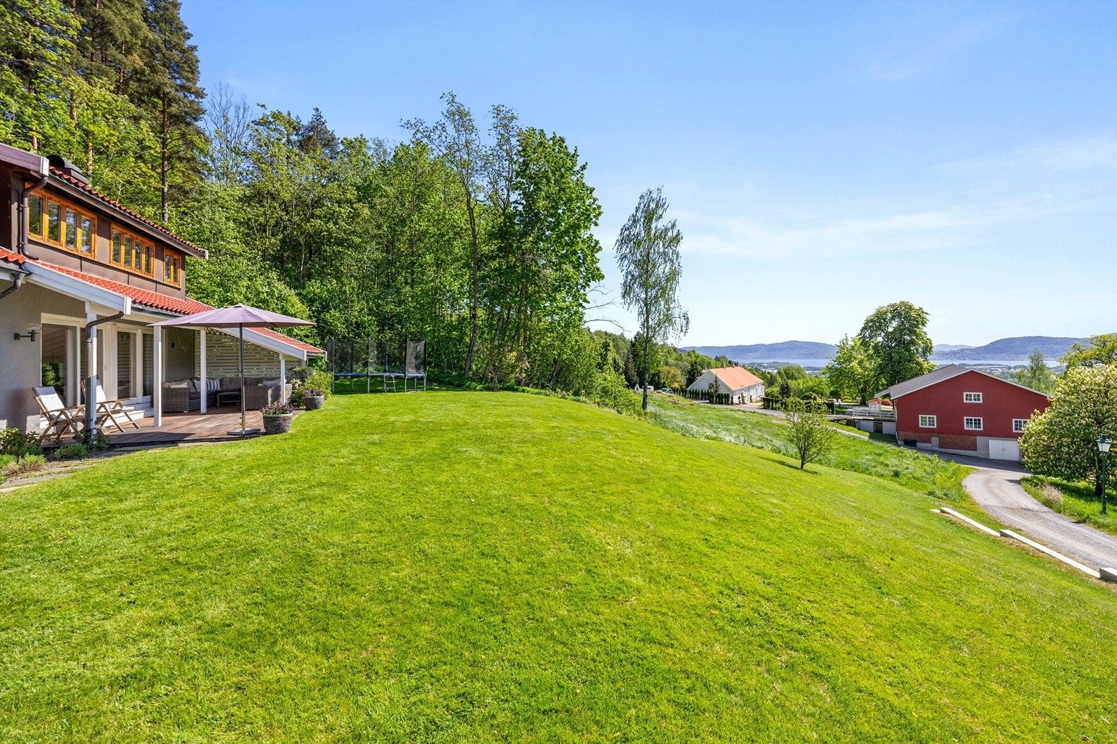 Lettstelt og romslig hageområde med gressplen, prydbusker og diverse beplantninger Galleribilde