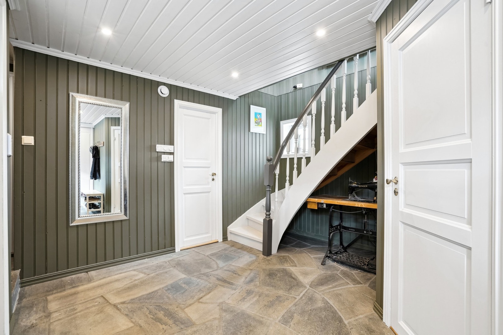 Entréen har god størrelse. Det er skifterfliser på gulvet og på veggene er det malt panel. Panelt himling med ledspotter. Galleribilde