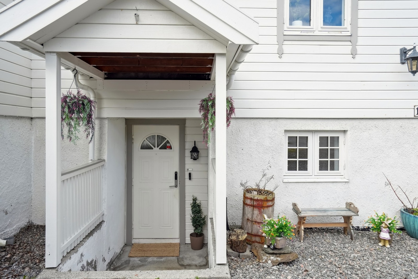 Entré med takoverbygg og belysning montert på veggen. Trapp ned. Galleribilde