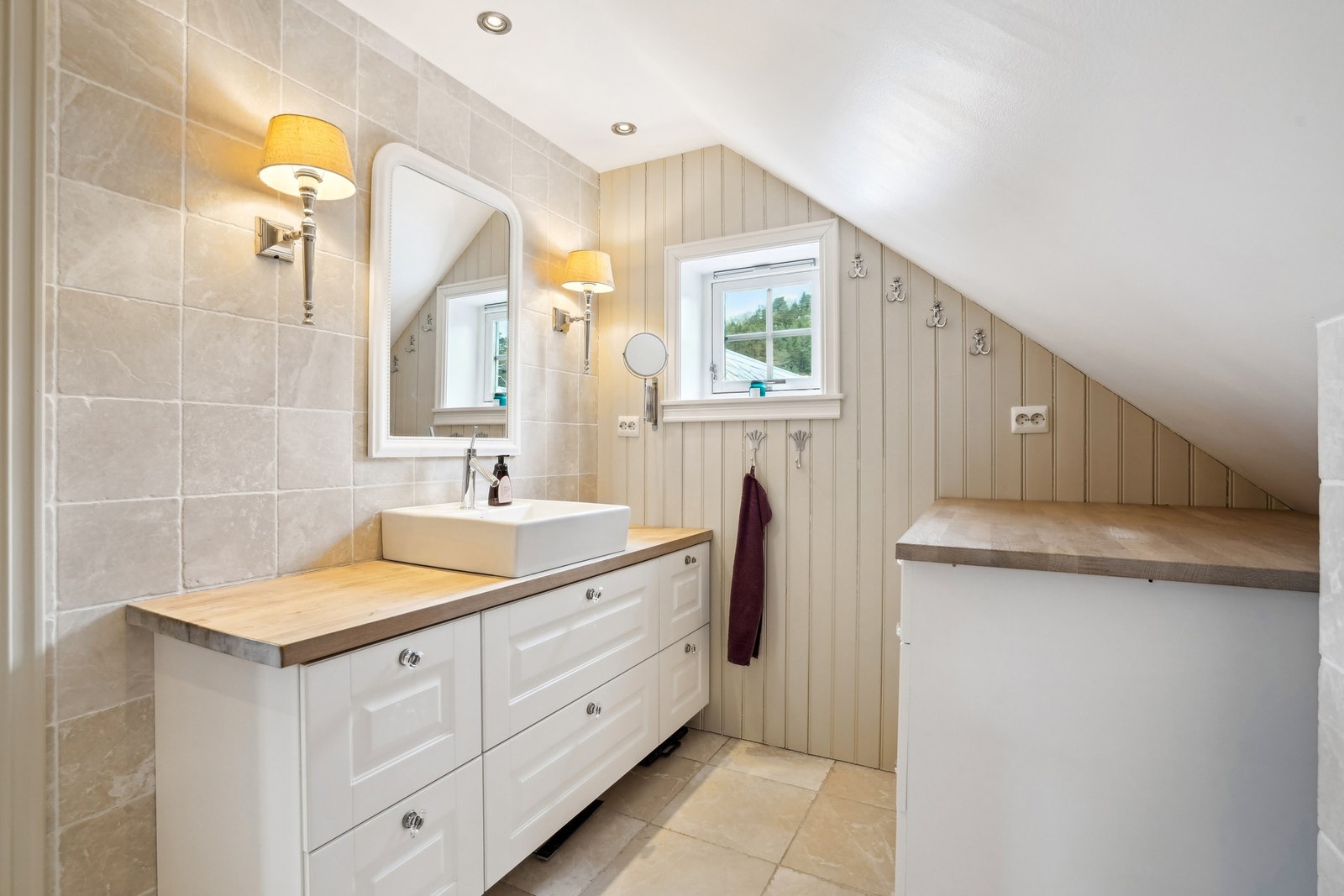 Lekre marmorfliser på gulv og delvis vegger. Elektriske varmekabler i gulvet. Innredning med god oppbevaringsplass. Badet har overflater og sanitært opplegg fra 2010. Galleribilde