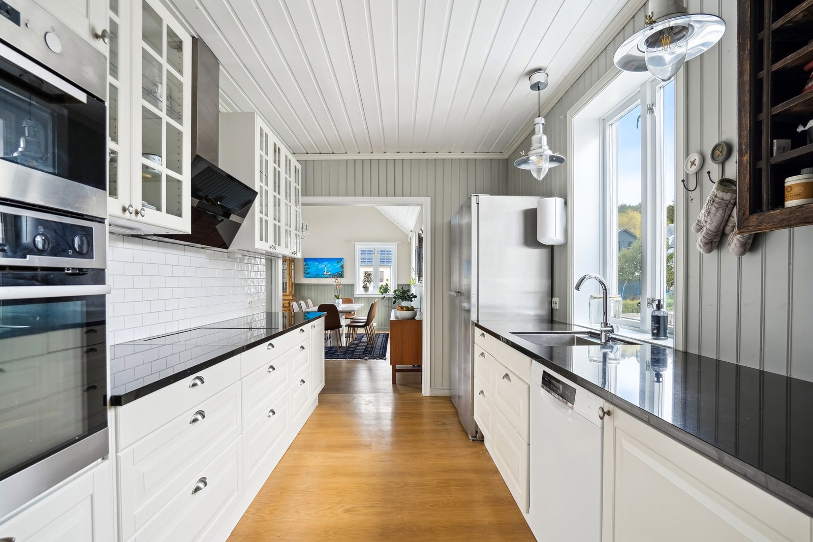 Kjøkkeninnredning fra Ikea med hvite profilerte fronter. Overskap med glassdører/sprosser og glasshyller. Kjøkkenventilator med avtrekk ut. Galleribilde