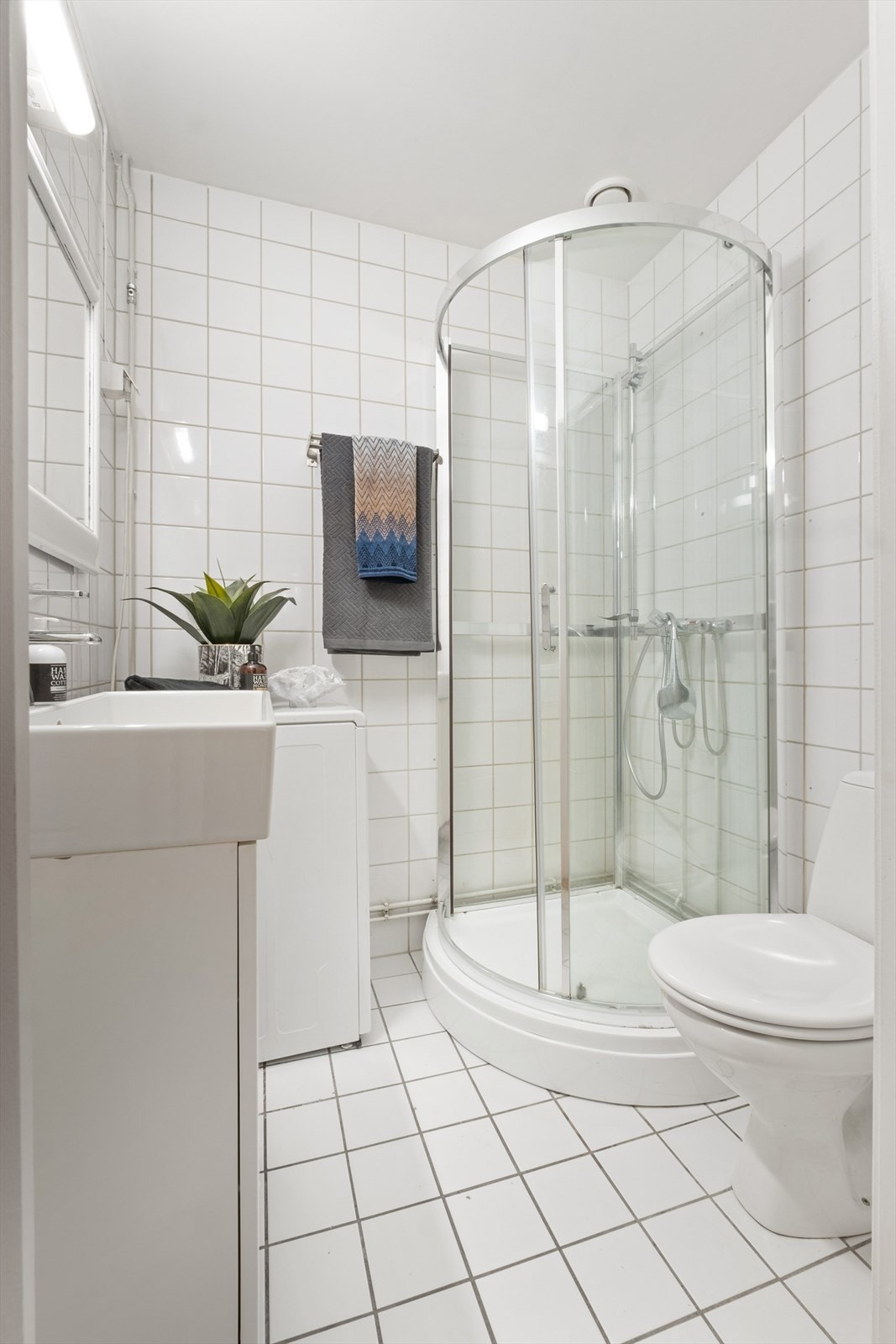 Pent baderom med flislagte overflater, gulvvarme og opplegg for vaskemaskin. Galleribilde