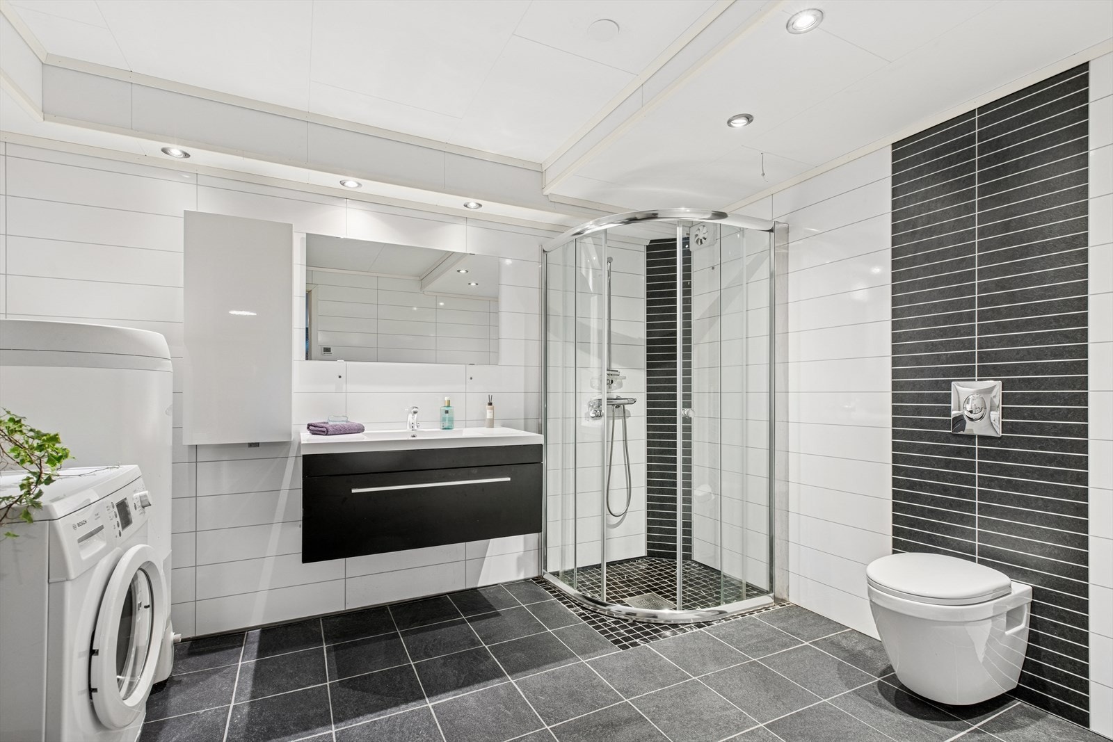 Pent og nyere bad fra 2015 i underetasje med baderomsplater på veggene og fliser på gulv med gulvvarme. Badet har baderomsinnredning med heldekkende servant og speil på vegg, vegghengt toalett og dusjhjørne. Galleribilde