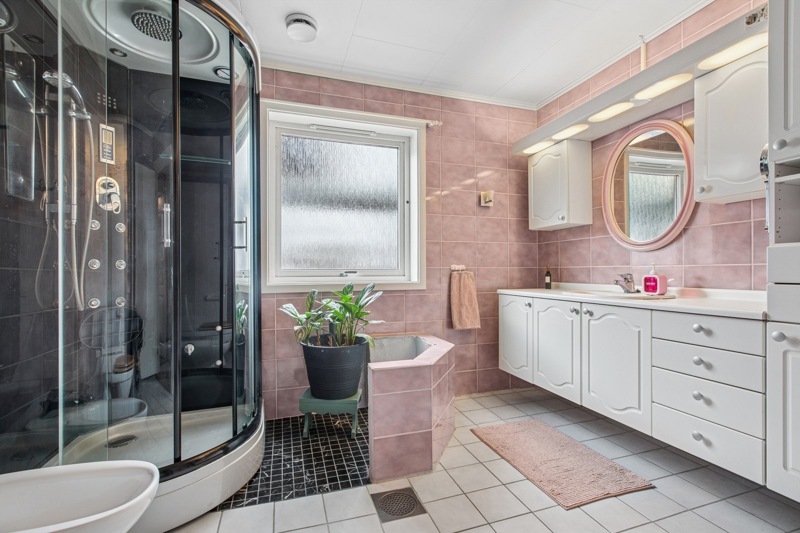 Bad 1. etasje har fliser på vegger og gulv. Badet har baderomsinnredning med heldekkende servant og speil på vegg, gulvstående toalett og dusjkabinett. Galleribilde